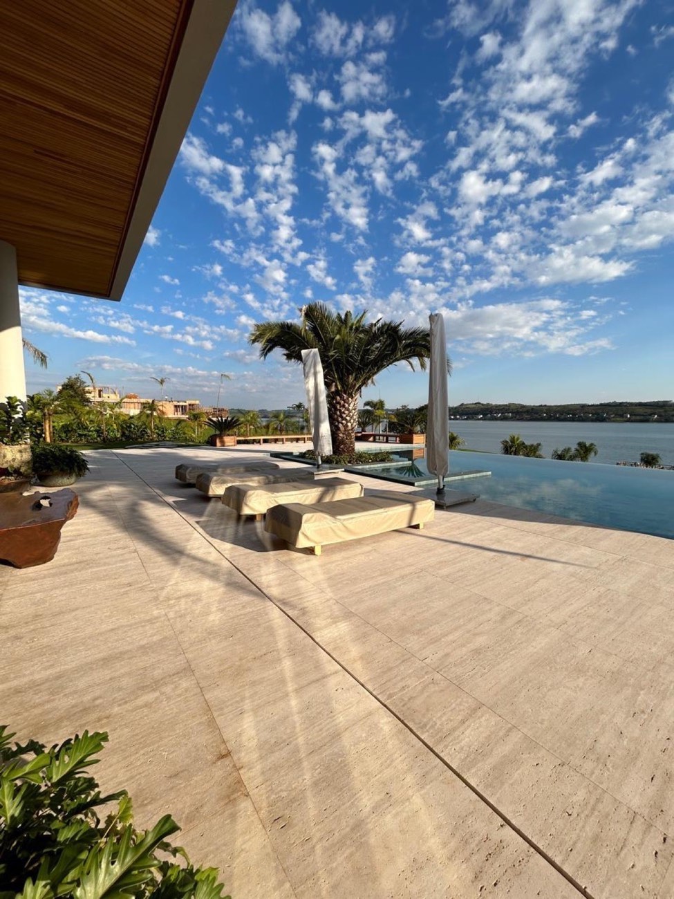Deck de borda infinita em travertino claro com palmeira
